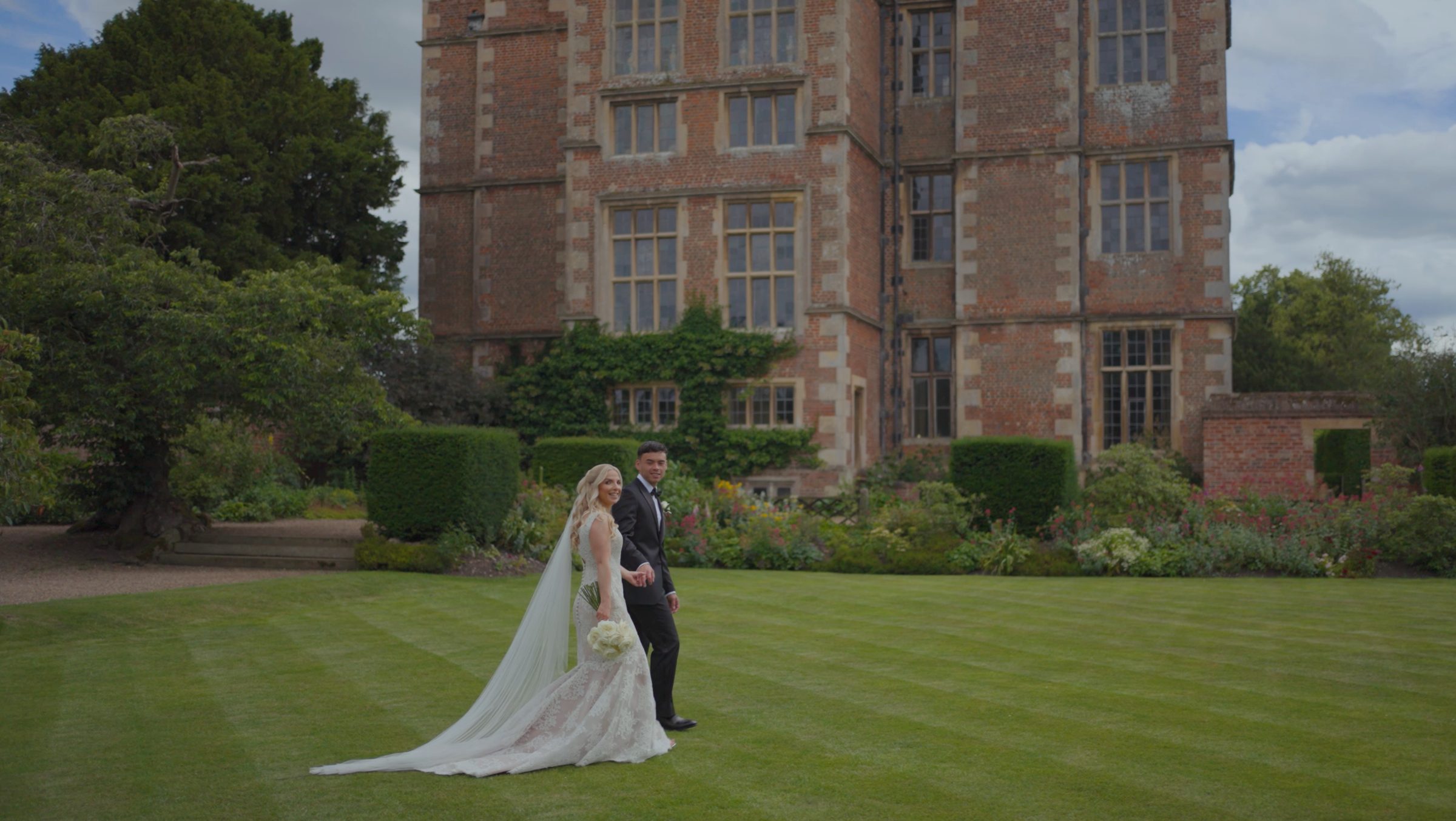 Bride and groom walking on the lawn of a country house